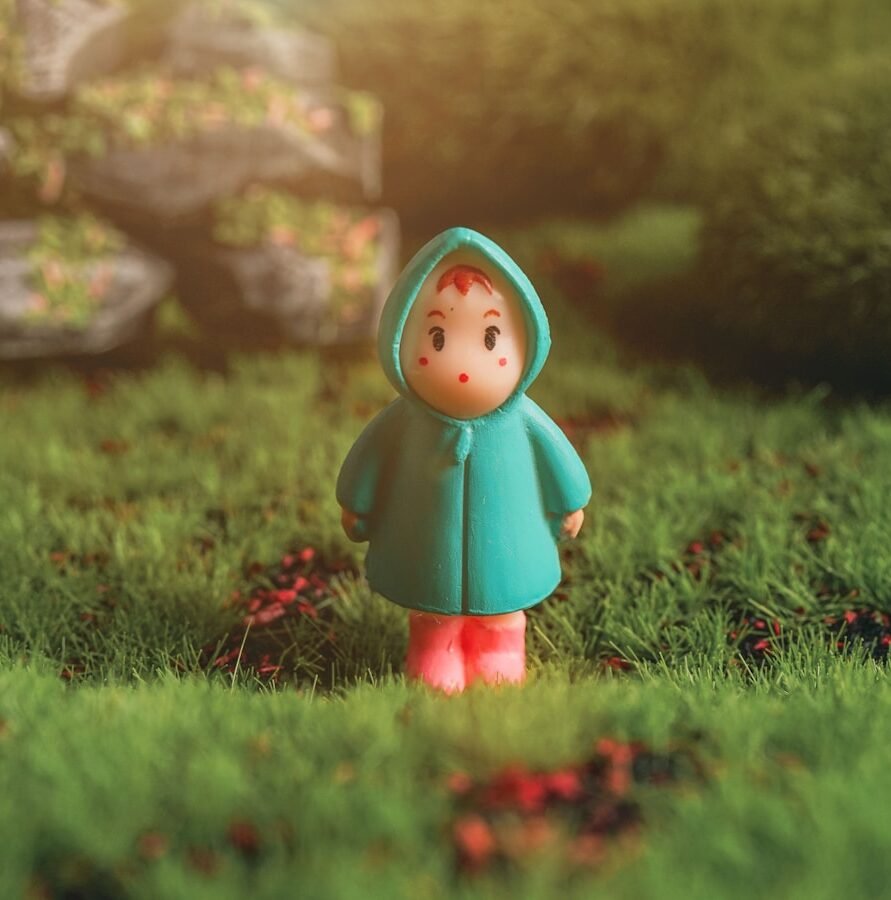 red haired girl in green dress figurine on green grass during daytime